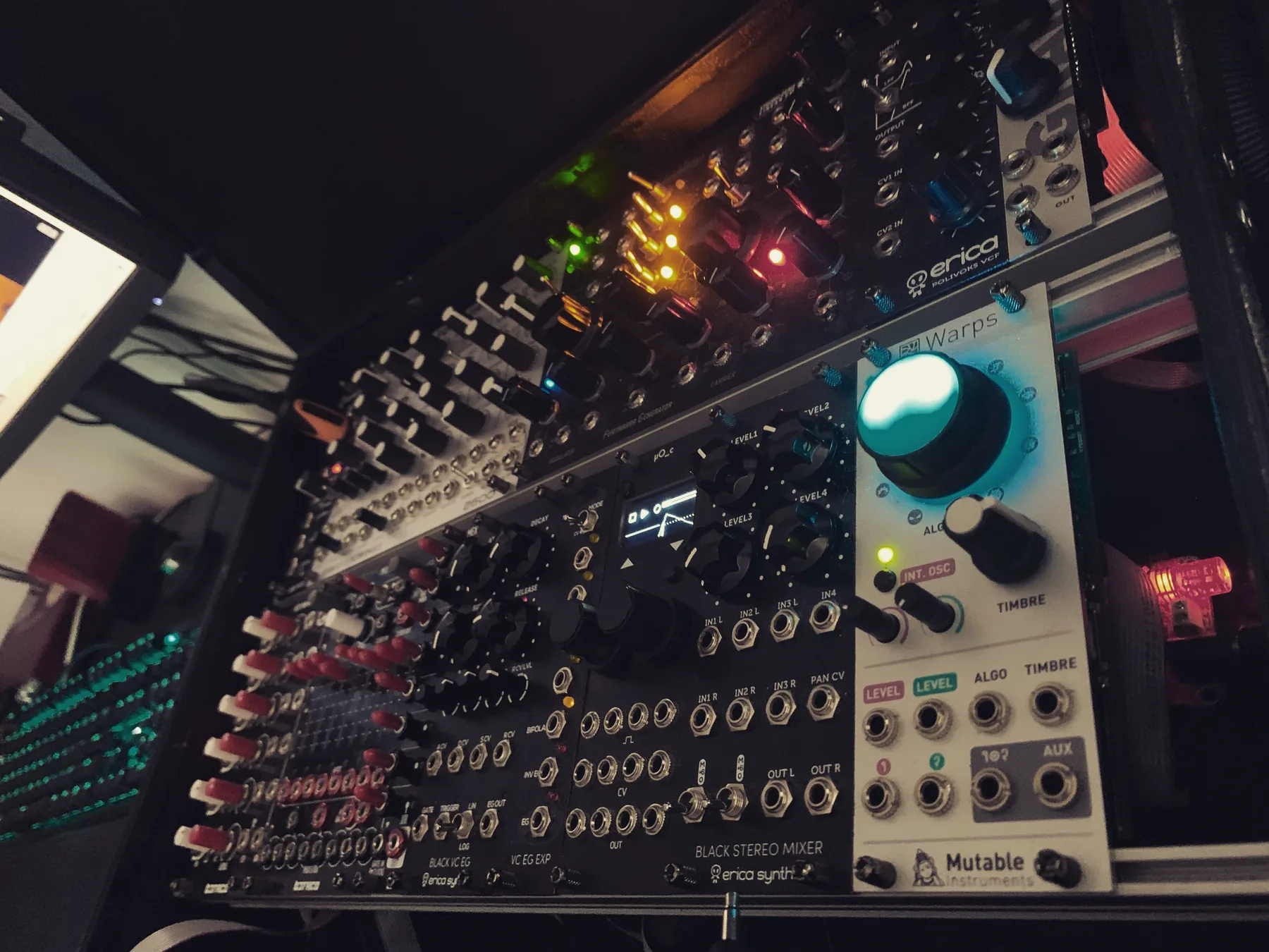 Modular synthesiser rack in the studio, lit by its own patch points